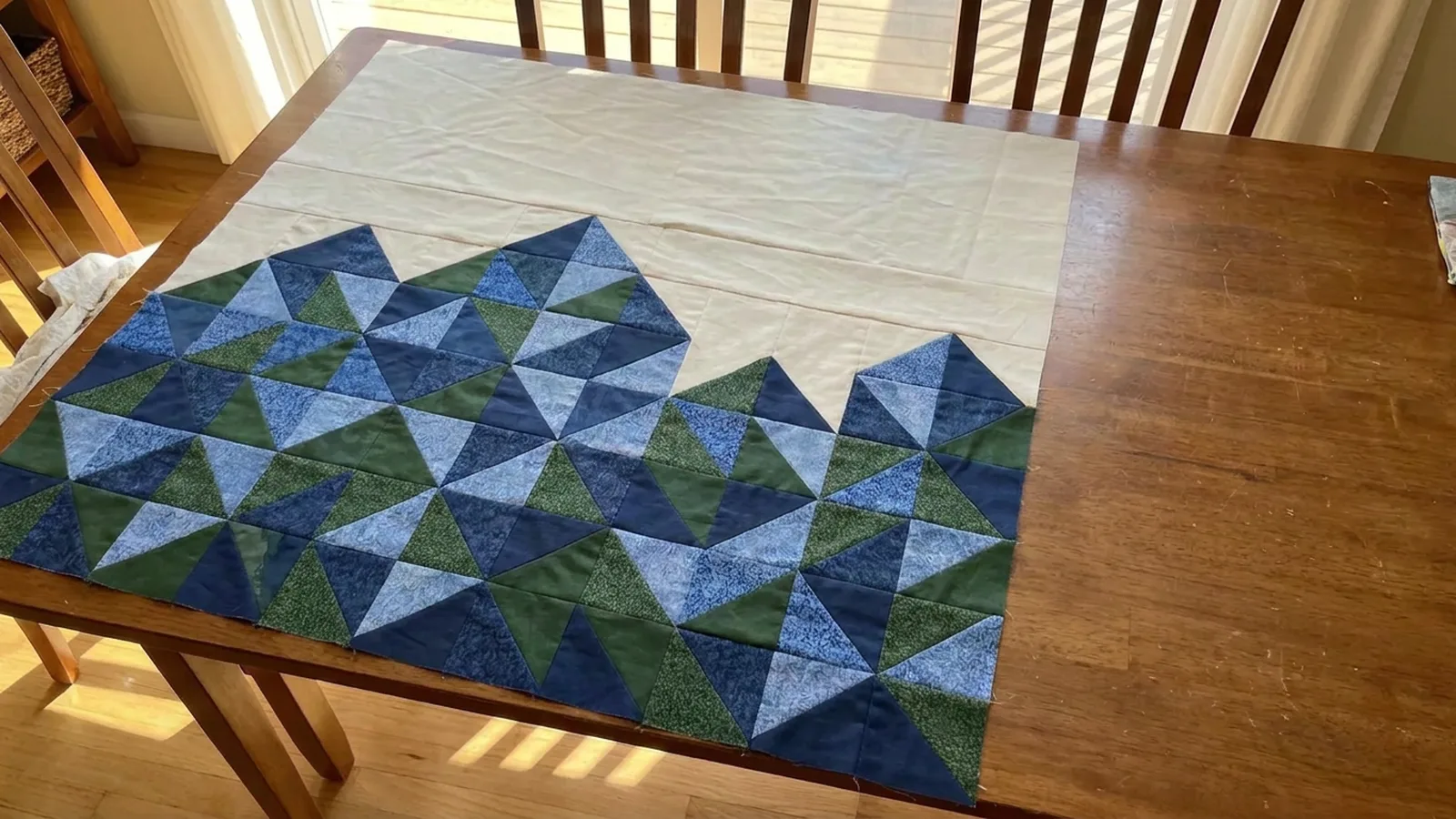Illustrative generated image of a blue and green triangle mountain quilt top on a dining table.