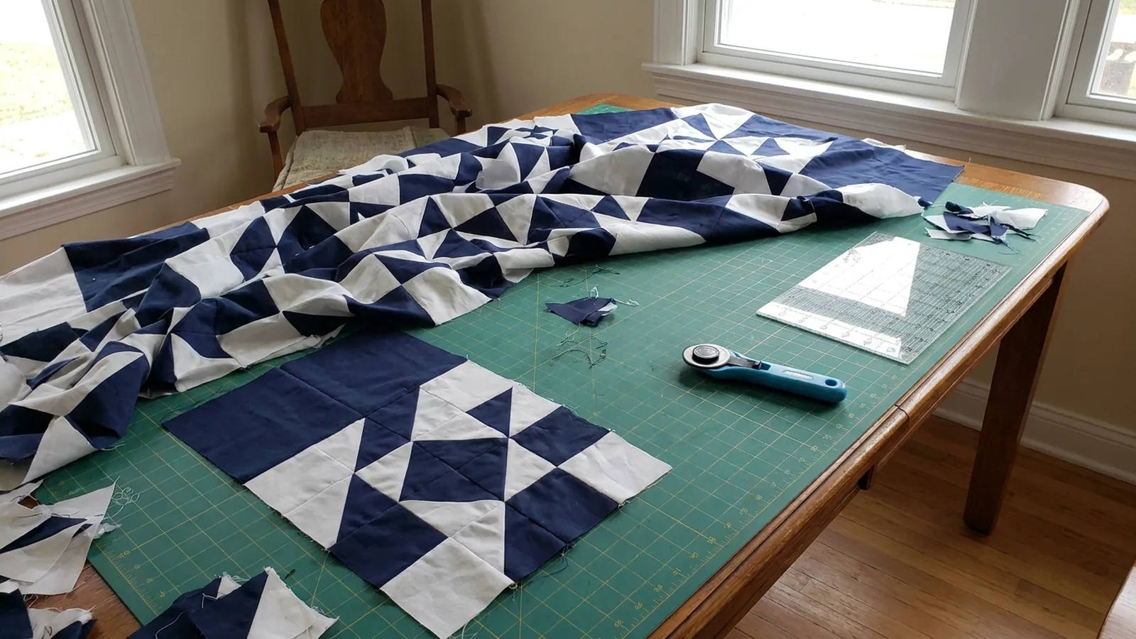 Illustrative generated image of a navy and white triangle quilt top in progress on a green cutting mat, with a rotary cutter and ruler.